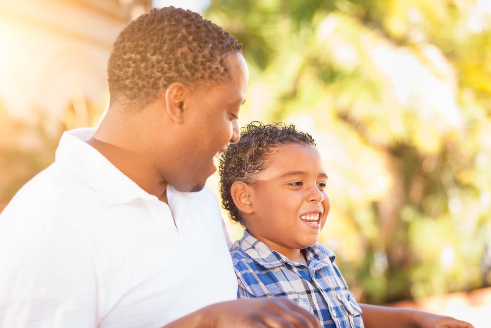 Black Son Sitting With Father Outdoors