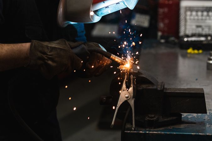 Anonymous mechanic welding metal construction in workshop