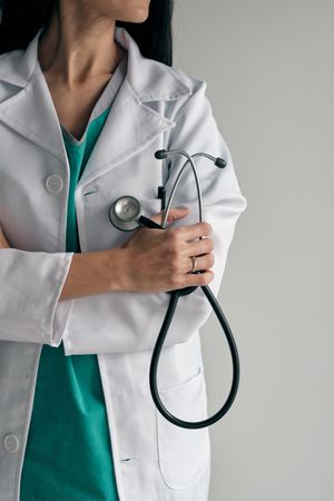 Crop confident physician with stethoscope and crossed arms