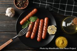 Top view of grilled sausages or hot dogs on a fork on dark ceramic plate with garlic bY9PDb