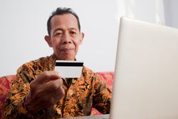 Older man looks at blank credit card