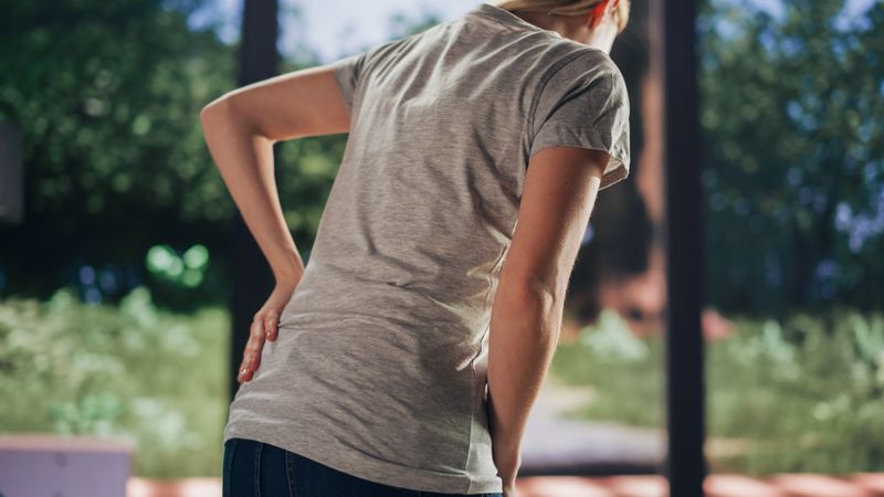 Human Going Through Severe Back Pain. Close Up of a Female Experiencing Discomfort in a Result of Spine Trauma or Arthritis.