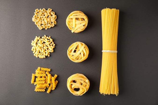 Flat lay composition with pasta on dark background, space for text