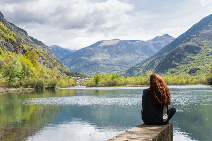 Carefree traveling woman enjoying freedom near lake in mountains