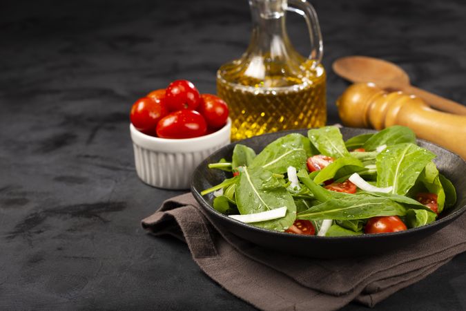 Arugula salad with tomatoes on dark background.