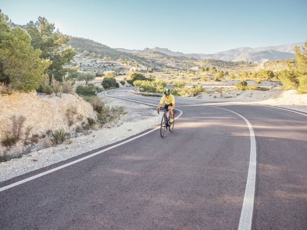 healthy man riding a bicycle on a mountain road in a sunny day