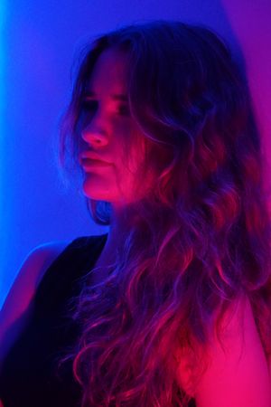 Portrait of teenage girl looking away in purple lit studio