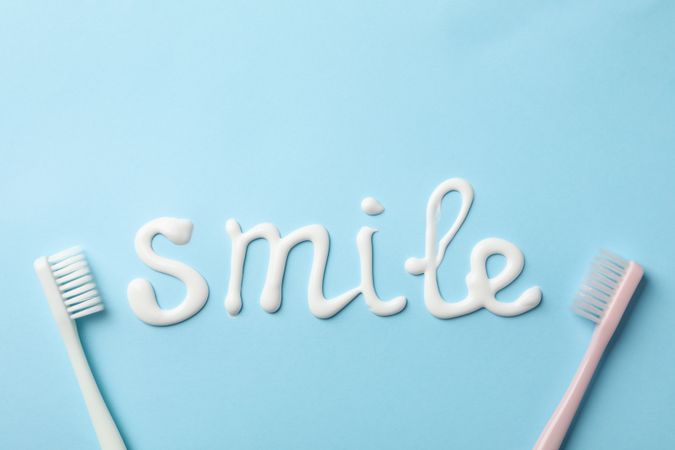 Word Smile made of toothpaste on blue background, top view