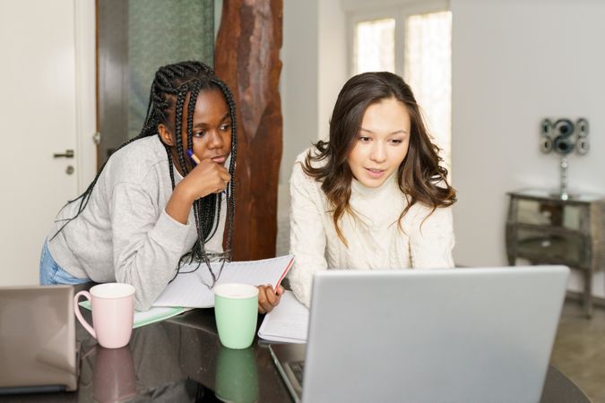 Two women sitting at kitchen table watching something on a pc