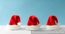 Three Santa Claus hats on blue background 0KVQDb