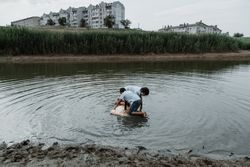 Kid brothers playing in dirty pond in daylight
