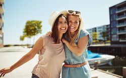 Two women happily walking together on sunny day next to river