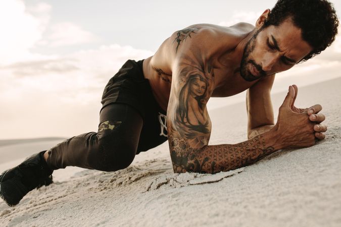 Healthy young man exercising on sand dunes