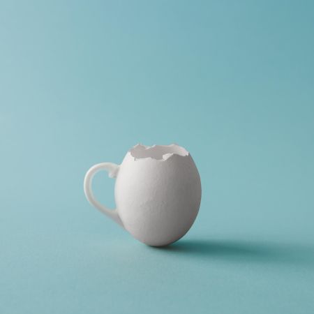 Egg shell coffee cup on pastel blue background