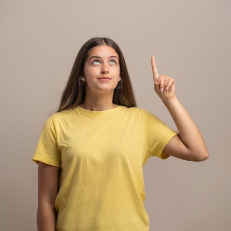 Young woman has an idea, looking and pointing up with inspiration.