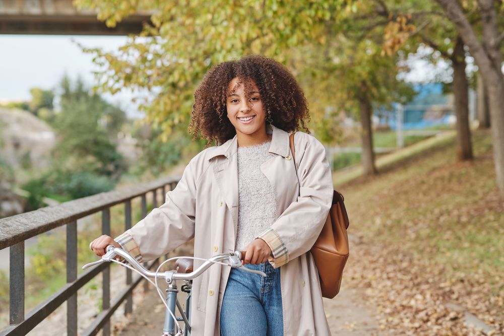 Positive Black Latina woman with bicycle in autumn day