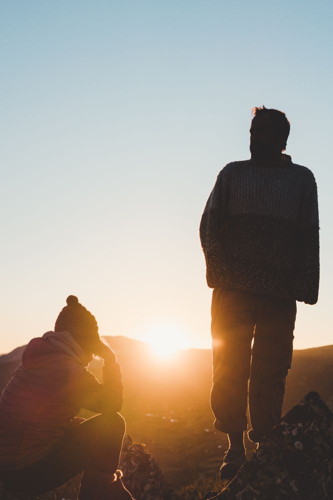 Man and woman enjoying sunset in autumn mountains
