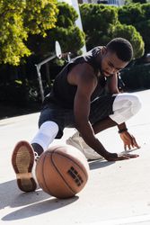 Black sportsman stretching on basketball court