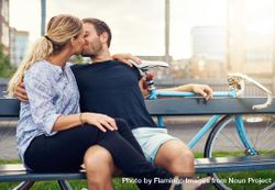 Cute couple kissing on bench taking a break while out on a bike ride 42jA74