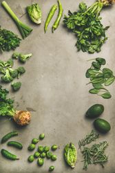 Arrangement of fresh green garden vegetables on concrete surface, copy space, vertical composition