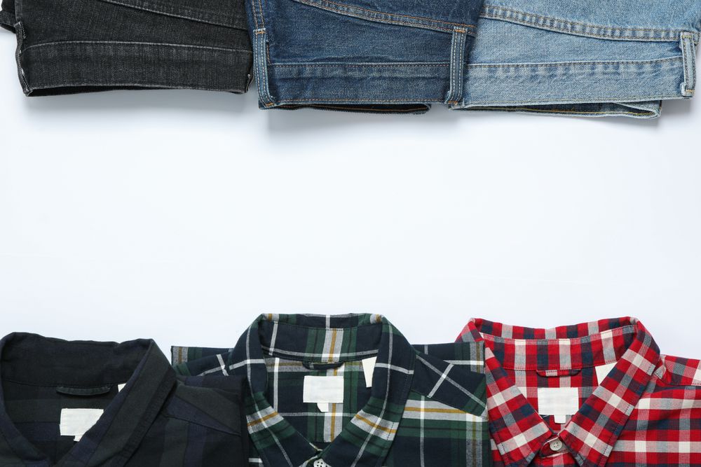 Flat lay with shirts and jeans on plain background