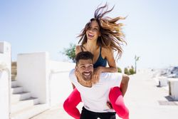 Smiling woman on her boyfriend’s back