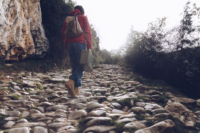 Woman with case walking on rocks above stream