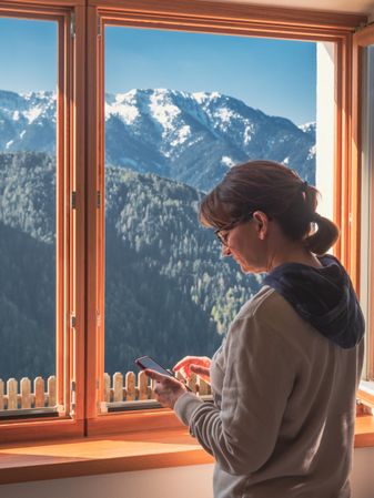 Woman browsing smartphone near window