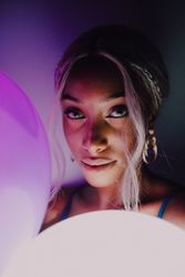 Black adult woman with illuminated balloon in darkness looking at camera