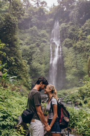 Couple in love standing near a waterfall in forest