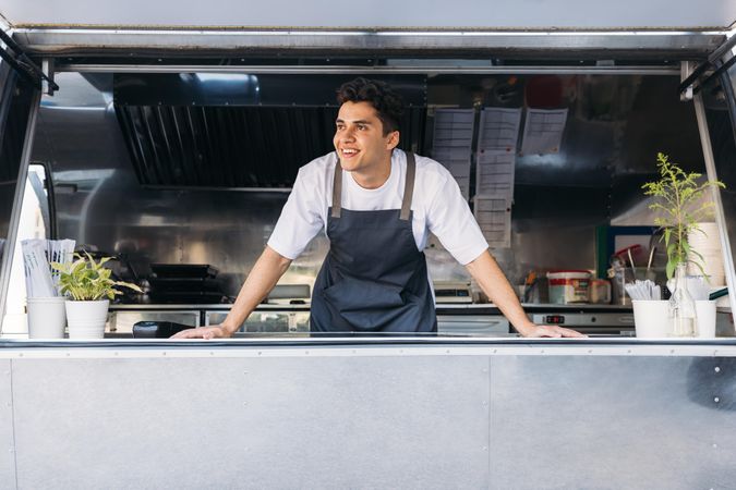 Smiling male food truck vendor in open kitchen