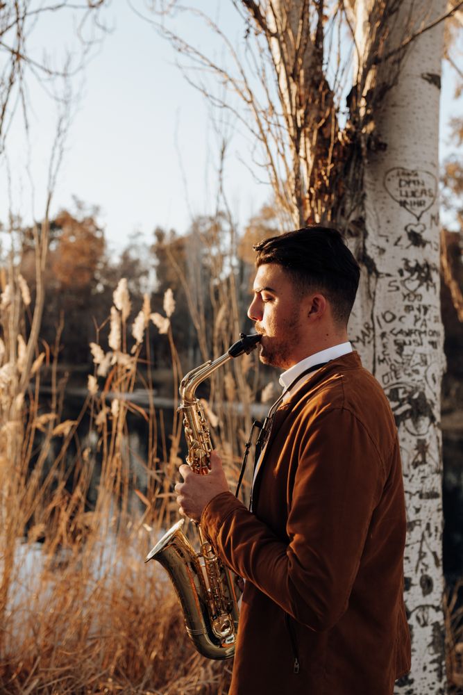 young musician playing the saxophone at sunset