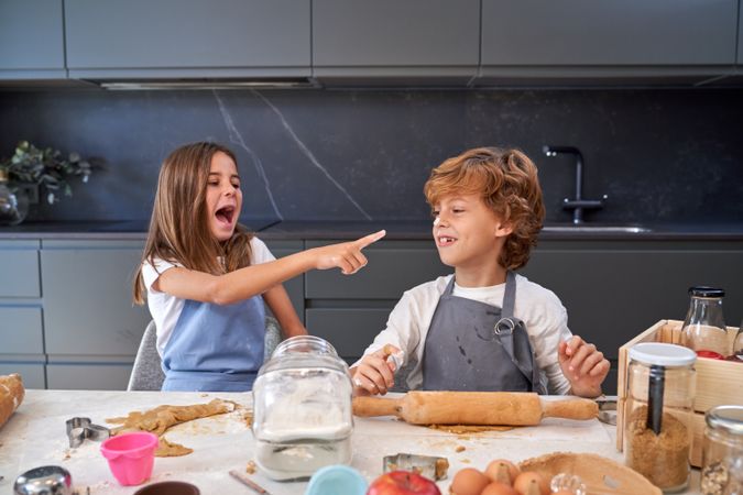 Girl with mouth opened pointing at nose of boy