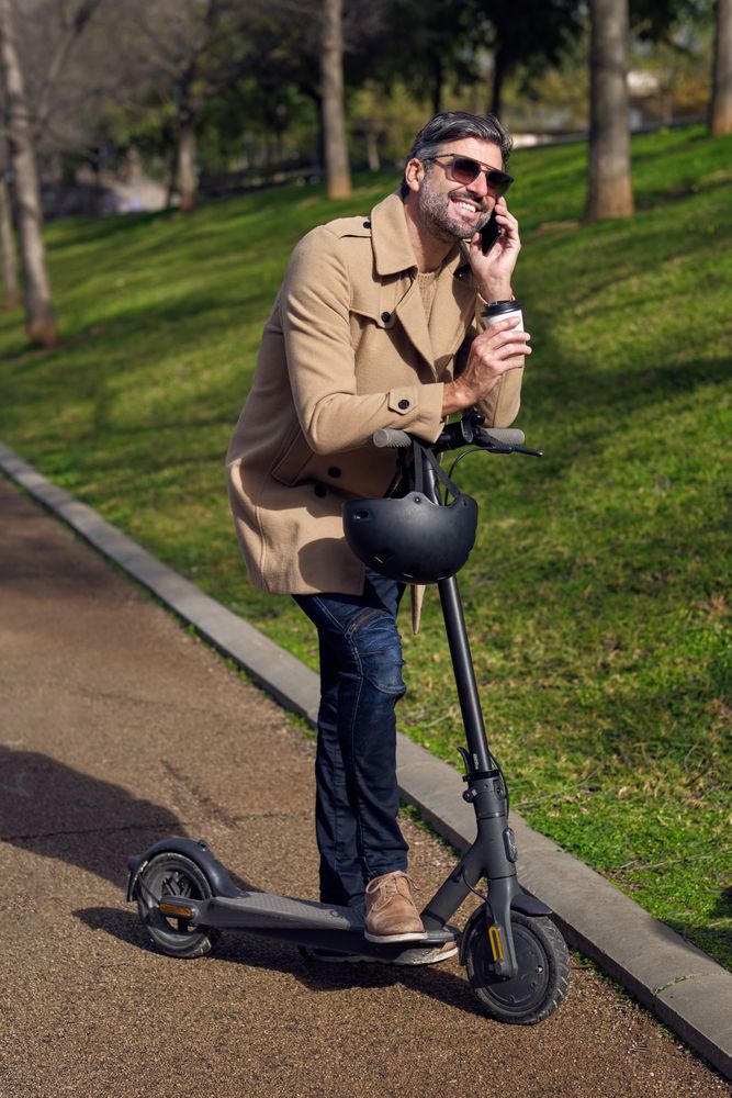Content man talking on smartphone on scooter