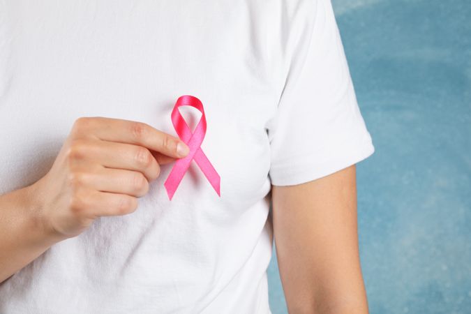 Person in t-shirt hold awareness ribbon against blue background