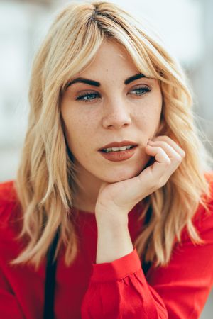 Contemplative blonde woman with head resting on her hand