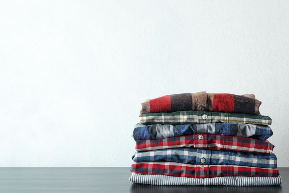 Stack of different shirts on table, space for text
