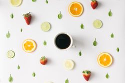 Colorful pattern made of citrus fruits, leaves and strawberries with cup of coffee