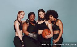 Beautiful group of women with sports equipment looking at camera against grey background 0gjEjb