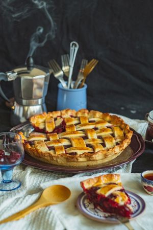 Warm fruit filled pie with steaming mocha pot in the background