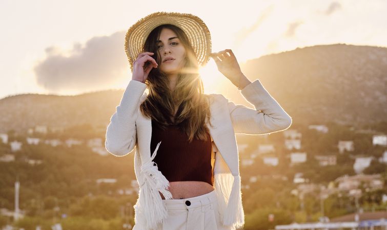 A long hair fashion model with a hat at the beach at sunset in a summer day