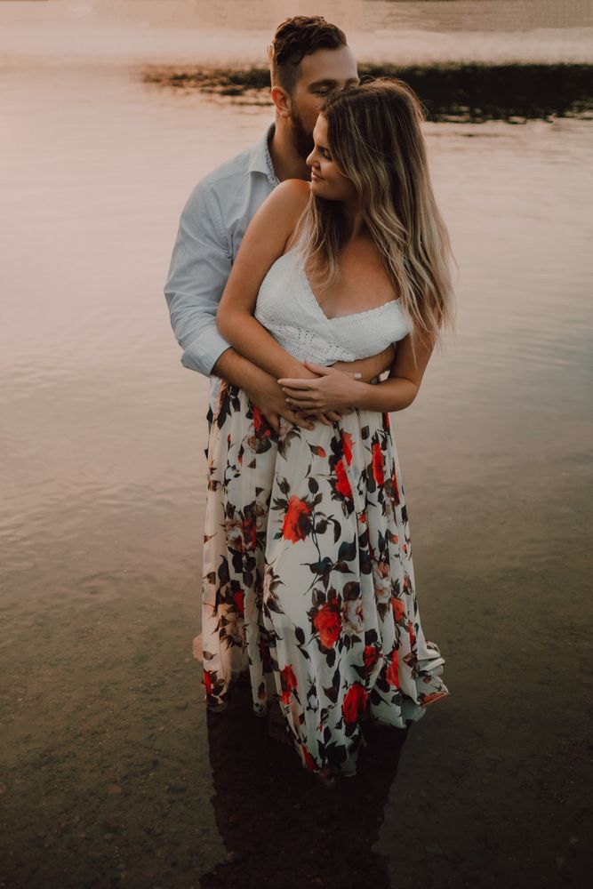 Loving couple hugging while standing ankle deep in water on beach