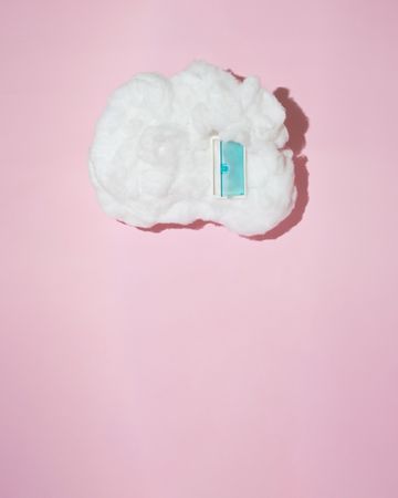 Single cotton cloud with blue door on pink background with copy space, vertical
