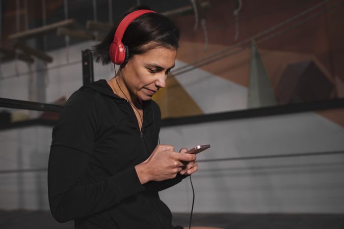 Woman with headphones and device sitting in gym