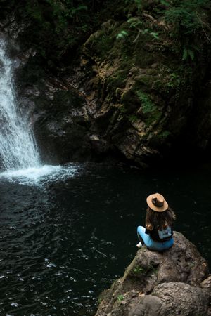Smiling woman sitting near waterfall
