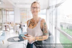 Tattooed woman with smartphone in a bright modern office 6begl5