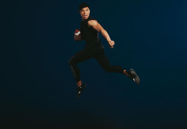 American football player in mid air holding a ball