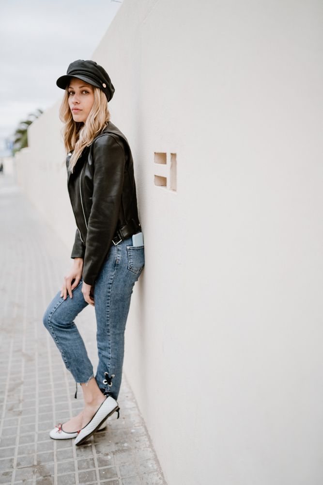 Stylish woman confidently leaning on white wall