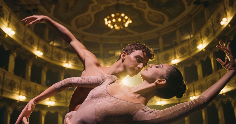 Close Up shot of Two Young Classical Ballet Dancers Performing on Theatre Stage with Dramatic Lighting.