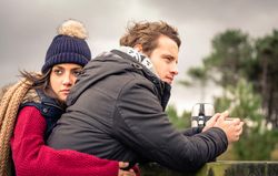 Woman holding her partner while he sips coffee on cold day